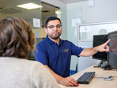 Staff member points at computer while helping student